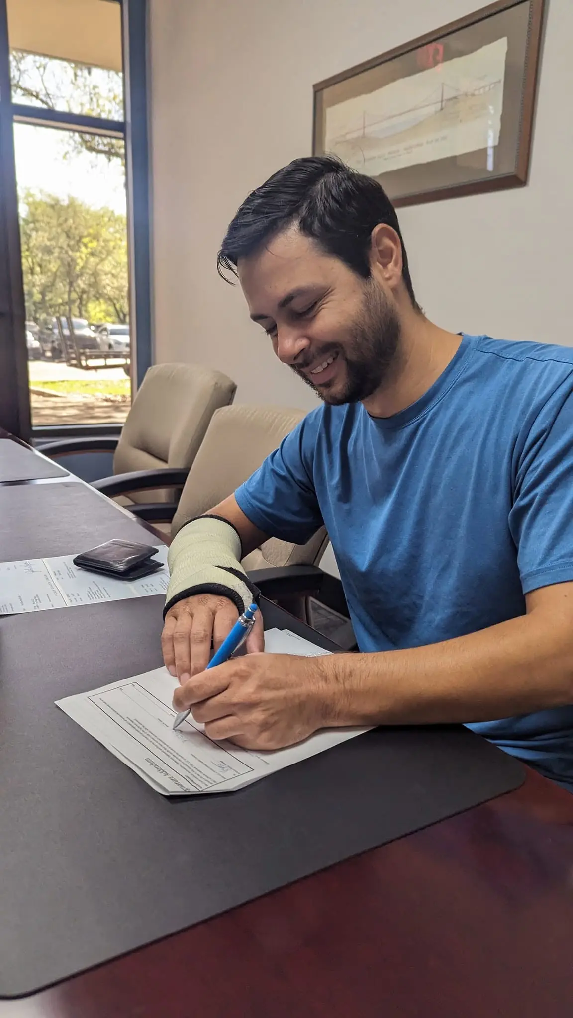 Kristiyan Rukov smiling as he signs the paperwork for a new house